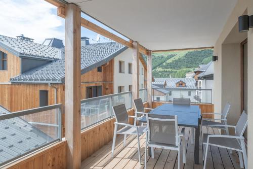 d'un balcon avec une table et des chaises bleues. dans l'établissement Alpe d'Huez Houses - Chez Cathy - Fermes de l'Alpe - Fabuleux 2 chambres neuf pour 6 personnes, à L'Alpe-d'Huez