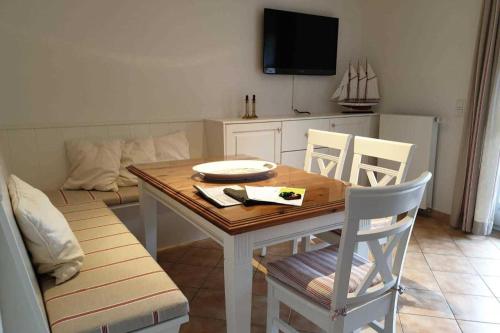 een eetkamer met een tafel, stoelen en een tv bij Hochstieg 32, Gonska, Haushälfte in Nieblum