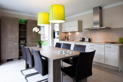 Una cocina con una mesa de madera y sillas negras. en die Strandhäuser - Meeresrauschen, en Ostseebad Sellin