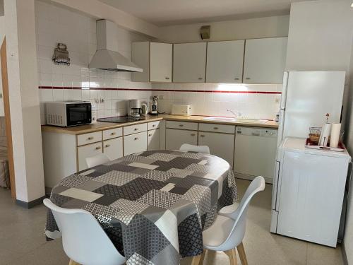 Il comprend une cuisine équipée d'une table en noir et blanc et d'un réfrigérateur. dans l'établissement Appartement 20, avec balcon, Résidence de l'Ars, à Aulus-les-Bains