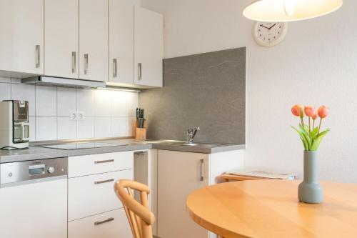 eine Küche mit einem Holztisch mit einer Blumenvase in der Unterkunft Seepark Sellin FeWo AG Whg 383 in Ostseebad Sellin