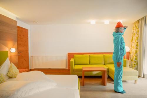 a person standing in a living room with a couch at Hotel Glemmtalerhof in Saalbach Hinterglemm