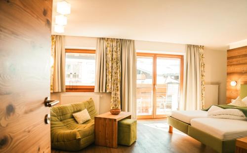 a bedroom with a bed and a couch and a chair at Hotel Glemmtalerhof in Saalbach Hinterglemm