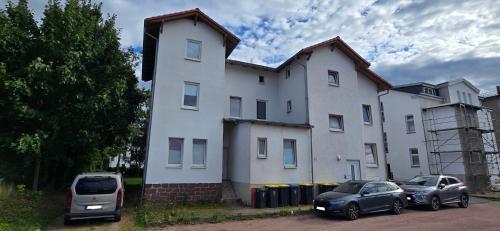 twee auto's geparkeerd voor een wit gebouw bij Ferienwohnung Roko in Eisenach