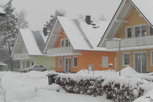 Una casa con nieve en el techo. en Ferienwohnungen Appartements - Ferienhaus Müritztraum, en Marienfelde