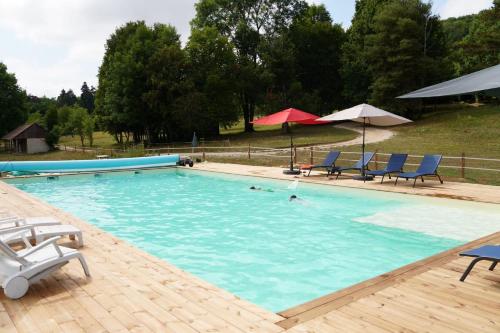 une grande piscine avec des chaises et des parasols bleus dans l'établissement Gîte du Colombier, à Lantenay