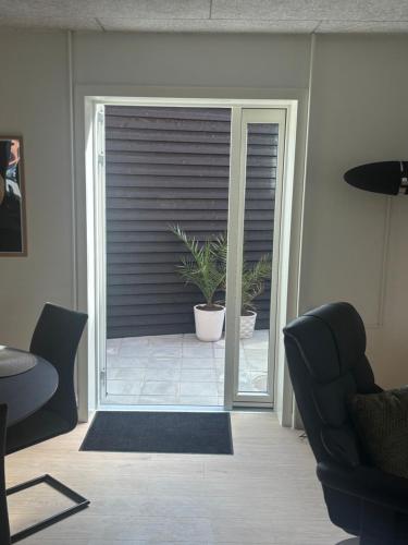 an open door to a patio with a plant at Ny lækker lejlighed på Havnen in Thyborøn
