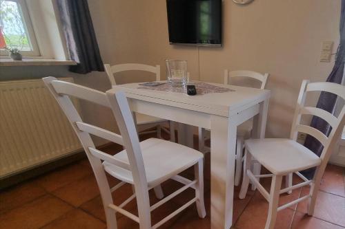 a white dining room table with chairs and a tv at Strandwiese,Haus Faltings Whg 1, EG in Goting