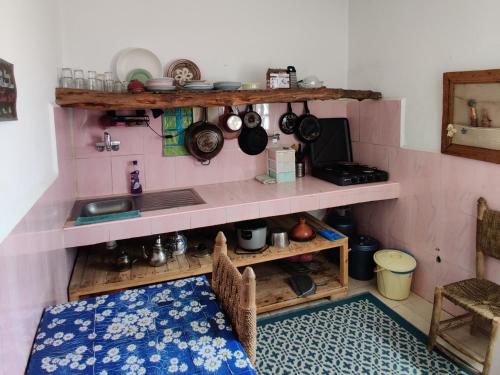 a kitchen with a sink and a shelf with pots and pans at Hippie Chic House in Sidi Kaouki