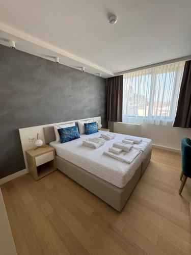 a bedroom with a large white bed with blue pillows at Apartmani Zepterme by CENTRAL in Vrnjačka Banja