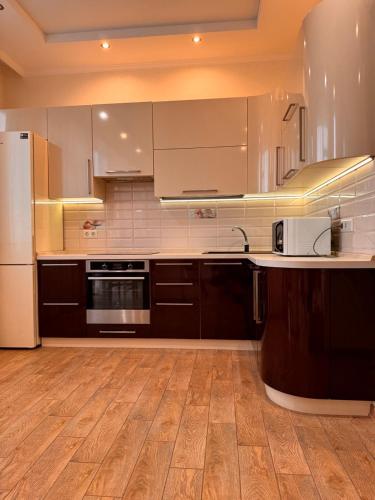 a kitchen with white appliances and a wooden floor at Апартаменты-студия с видом на море ЖК Kadorr 10 жемчужина in Odesa