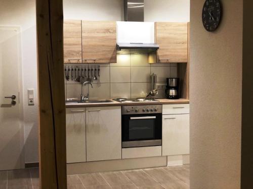 eine Küche mit weißen Schränken und einem Herd mit Backofen in der Unterkunft Ferienwohnung "Landblick" in Tecklenburg