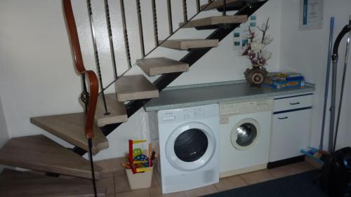 a laundry room with a washing machine and a staircase at FeWo Sassen in Ihlow