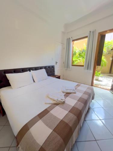 a bedroom with a large white bed with towels on it at Casa Jeri Guarani in Jericoacoara