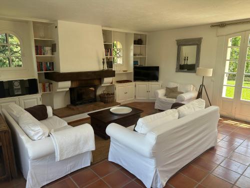 Elle comprend un salon doté d'un mobilier blanc et d'une cheminée. dans l'établissement Villa Hass, à Mandelieu-la-Napoule