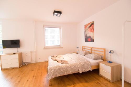 a white bedroom with a bed and a television at HAPPYESTATE ul Biskupia 3 min do Rynku in Wrocław