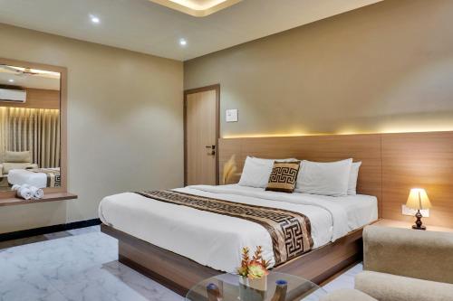 a bedroom with a large bed and a mirror at Hotel Sayba Classic in Pandharpur