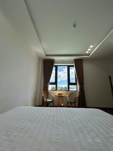 a bedroom with a bed and a table and chairs at Hilaria Hotel in Vạn Ninh