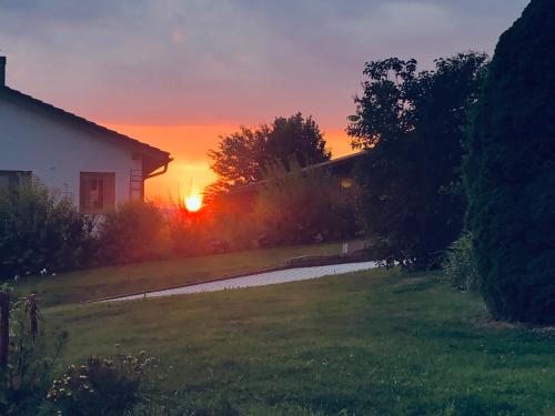 a sunset over a house with the sun setting in the background at Ferienwohnung Haus Veronika in Wegscheid
