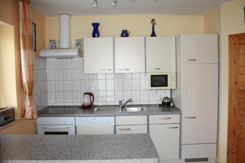 a kitchen with white cabinets and a sink and a refrigerator at Ferienwohnung Haus Veronika in Wegscheid