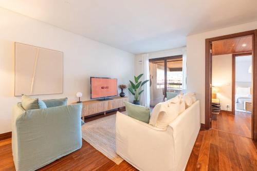 TorreにあるGuestReady - Sunny comfort with a balcony and poolのリビングルーム(白い椅子2脚、薄型テレビ付)