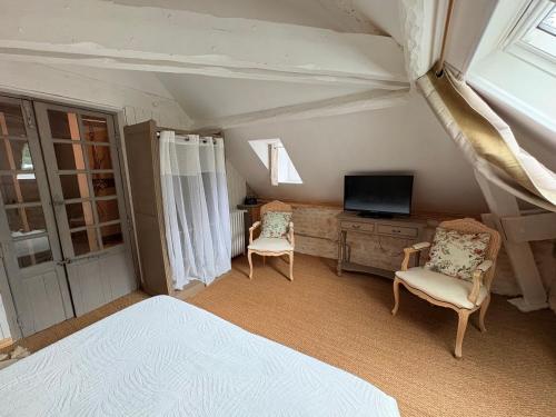 a bedroom with a bed and a tv and chairs at Chambre duo in Sainte-Gemme-la-Plaine