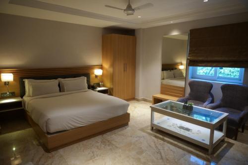 a bedroom with a bed and two chairs and a table at LUXUS INN in Dhanbād
