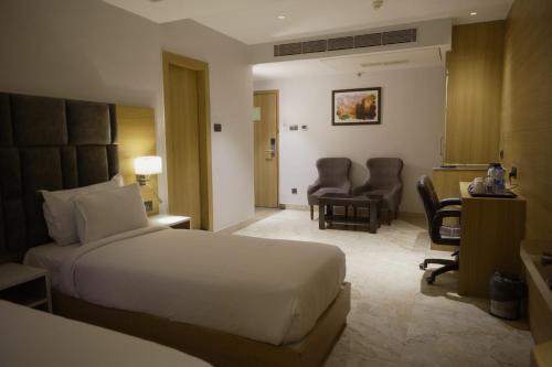 a hotel room with a bed and a desk and chairs at LUXUS INN in Dhanbād