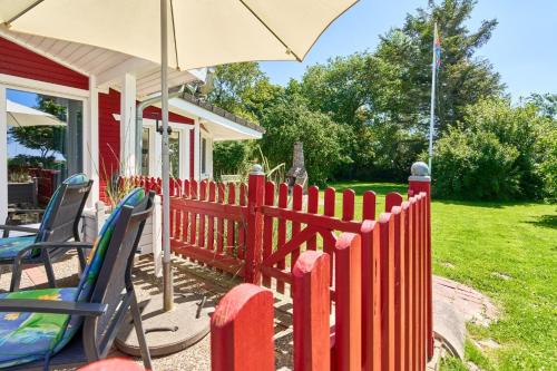 a red fence next to a house with an umbrella at Horn sien Hus in Simonsberg