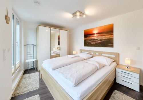 a bedroom with a large white bed with a painting on the wall at Ocean Dream 2, FeWo 4 in Duhnen