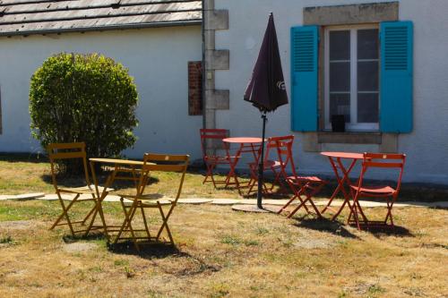 a group of chairs and tables and an umbrella at Chambre Nacre in Maisonnais