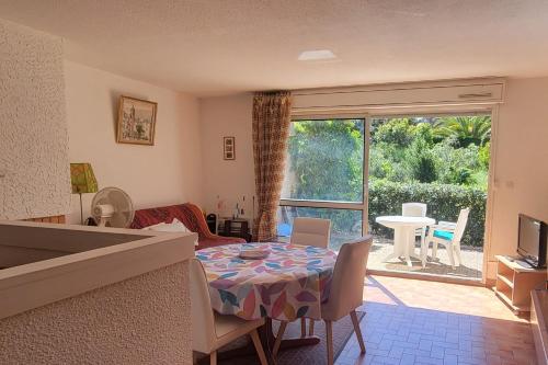 un salon avec une table et des chaises et une fenêtre dans l'établissement Apartment with garden - near beach, à Fréjus
