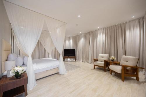 a bedroom with a canopy bed and a television at Regency Sealine Camp in Mesaieed