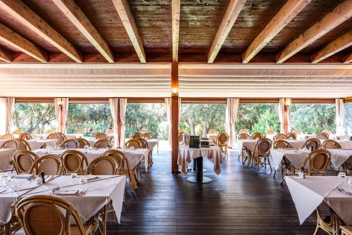a dining room with tables and chairs and windows at Roccamare Resort - Casa di Ponente in Castiglione della Pescaia