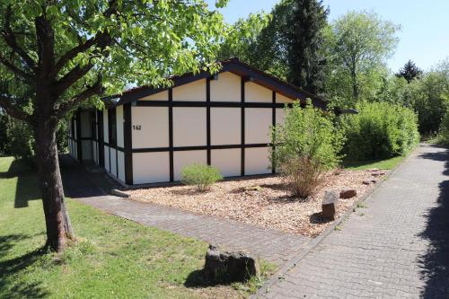 a garage with a tree and a sidewalk at Ferienhaus Robinson Romantikpfad 162 in Waldbrunn
