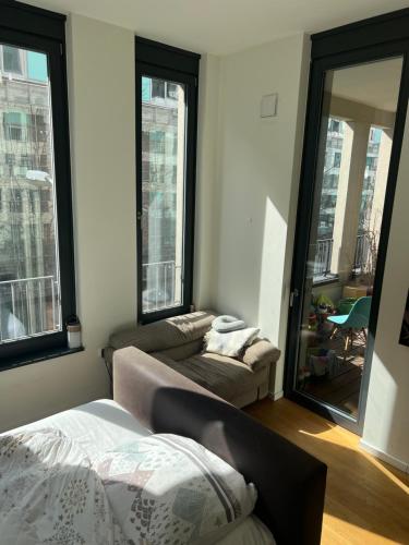 a bedroom with a bed and a couch and windows at Berlin -Central-Mitte Light Filled 2BD in Niederdorla