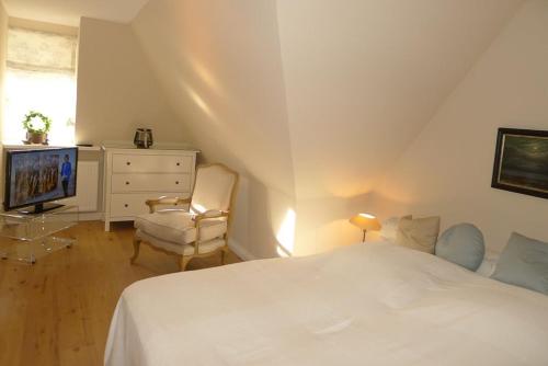 a bedroom with a bed and a tv and a chair at Haus Westerheide in Nieblum