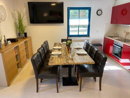 a dining room table with black chairs and a kitchen at Familienfreundliches Reetdachhaus Weissdorn 2 in Puddemin