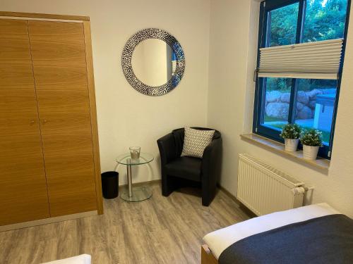 a bedroom with a chair and a mirror on the wall at Familienfreundliches Reetdachhaus Weissdorn 2 in Puddemin