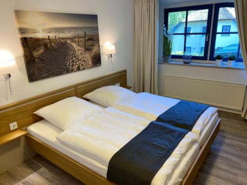 a bedroom with a bed with a painting on the wall at Familienfreundliches Reetdachhaus Weissdorn 2 in Puddemin