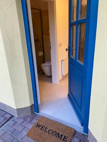 a blue door leading to a bathroom with a toilet at Familienfreundliches Reetdachhaus Weissdorn 2 in Puddemin