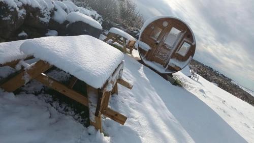a bench covered in snow next to a mirror at Unique Home with Outdoor Sauna in Connemara in Galway