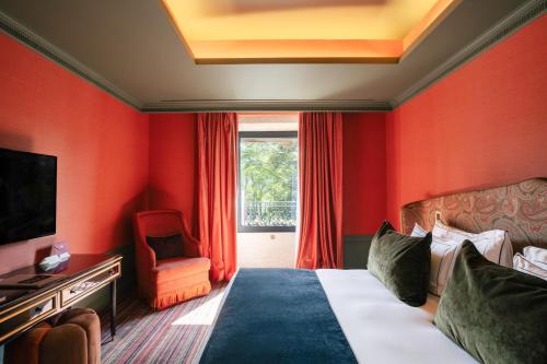 a hotel room with red walls and a bed and a chair at Vinha Boutique Hotel - The Leading Hotels of the World in Vila Nova de Gaia