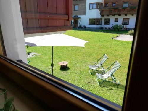 a view of a yard with two chairs and an umbrella at Gästehaus Sonja in Niederau