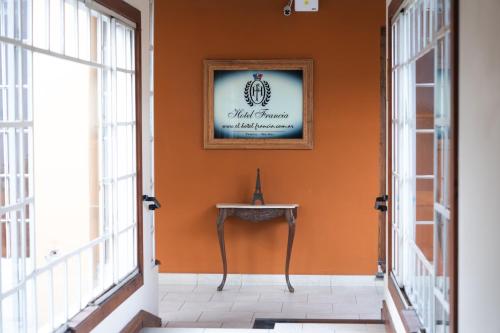 an orange hallway with a table and a picture on the wall at Hotel Francia in Tandil