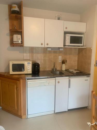 une cuisine avec des armoires blanches et des appareils électroménagers blancs dans l'établissement Les Thymels, à Valloire