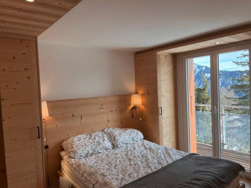ContheyにあるChalet les jougesのベッドと大きな窓のある寝室
