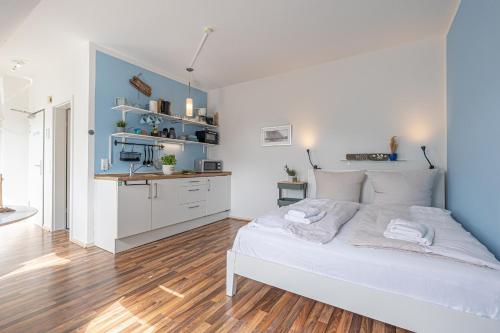 a bedroom with a white bed and a kitchen at fewo1846 - Strandresidenz Wassersleben AHOI - strandnahes Studioapartment im Dachgeschoss in Harrislee