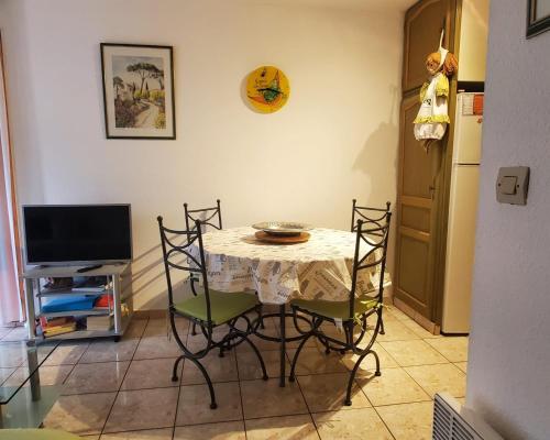 une table à manger avec des chaises et une télévision dans l'établissement Centrally located apartment with swimming pool, à Fréjus