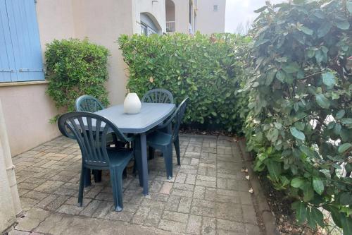 une table avec quatre chaises et un vase sur elle dans l'établissement Centrally located apartment with swimming pool, à Fréjus